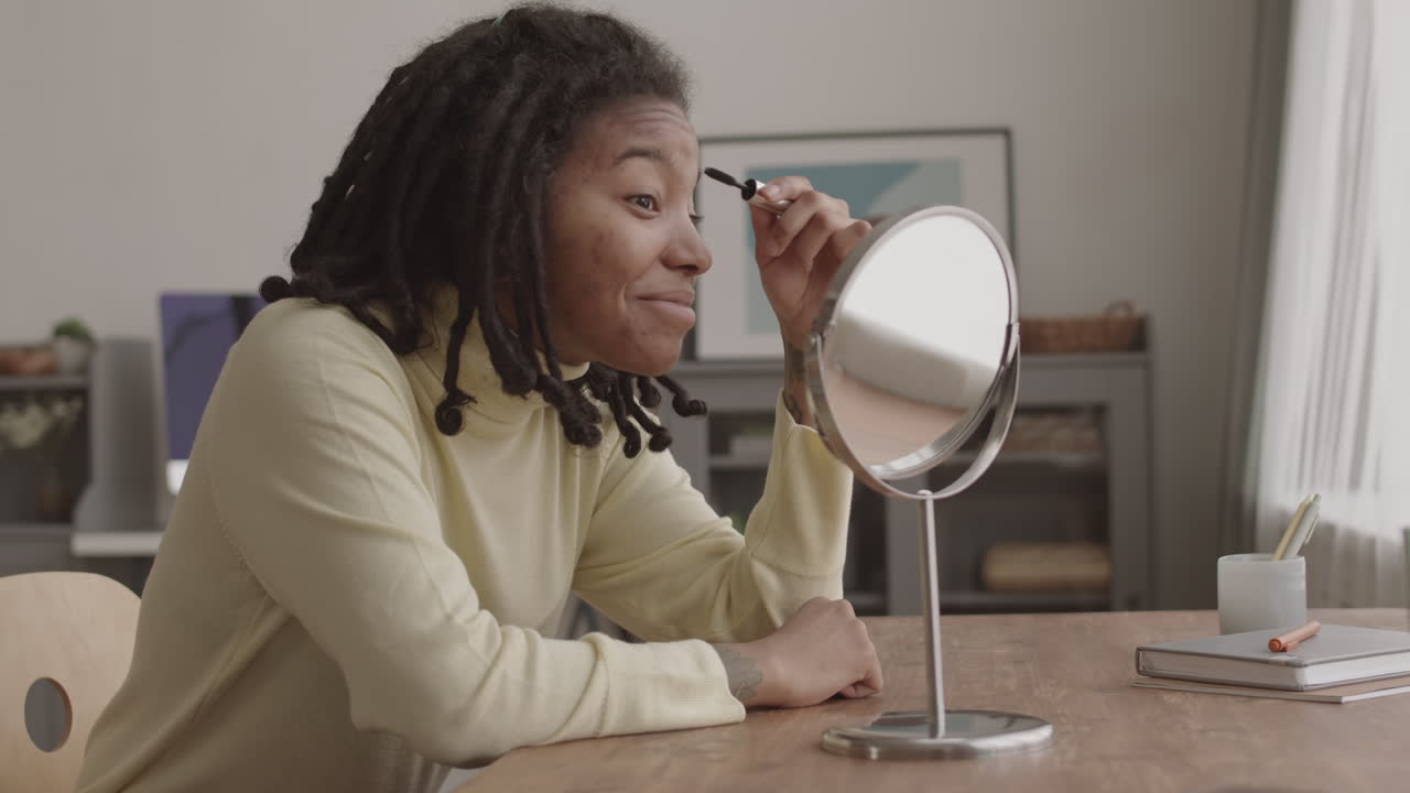 Young Woman Doing Makeup in front of Mirror