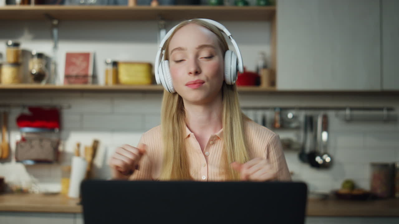 Woman enjoy online music by headset on remote work break close up. Girl dancing.