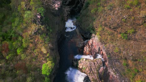 Stunning Dos Couros waterfall plunging into a deep canyon surrounded by vibrant vegetation in Chapada dos Veadeiros national park, showcasing the raw beauty of brazilian nature, static drone tilt up