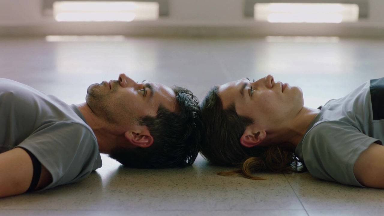 Lying couple breathing, blinking on hard floor, clip starting under bright panel, wearing grey tees