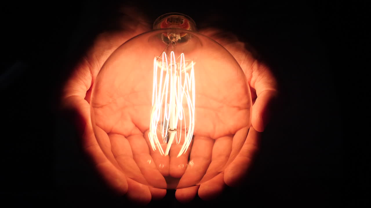 대형 빈티지 전구가 백인 남성의 손에 빠르게 깜박입니다.