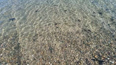 Slow-motion-sunlit-patterns-dancing-across-shallow-transparent-ocean-tide