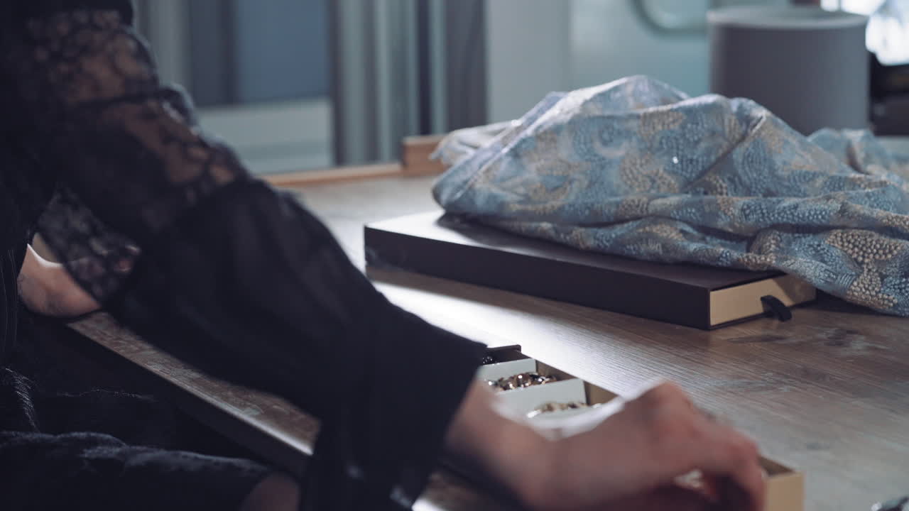 Tailor is opening box with beautiful sewing buttons on the background of workshop. Dressmaker's hands taking box with different buttons for sewing in atelier.
