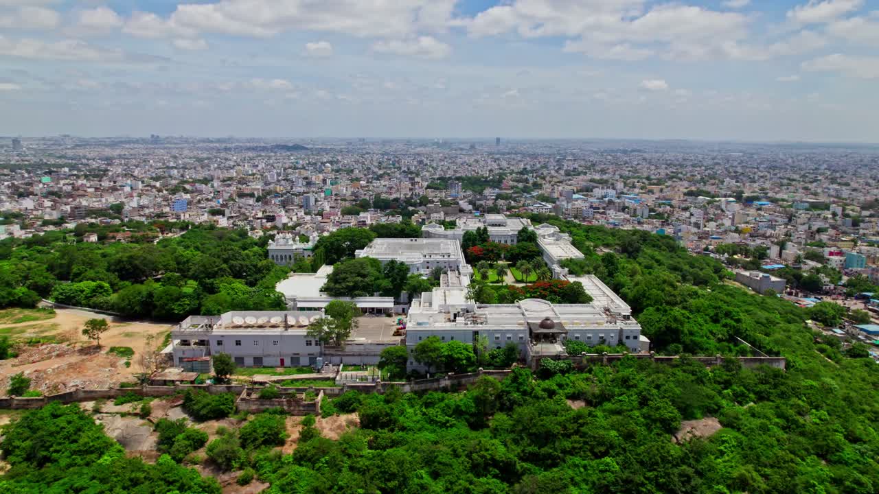 Taj groups luxury hotel falaknuma palace in hyderabad with trees and cityscape at engine bowli, falaknuma, hyderabad, telangana, india. day time, drone shot, 4k.
