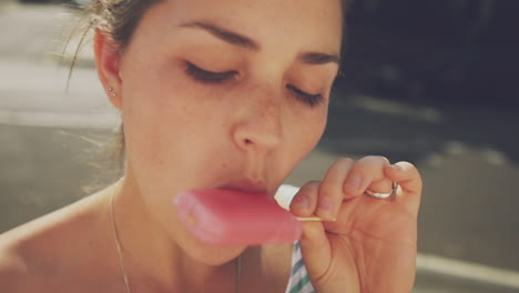 woman eating a pink popsicle