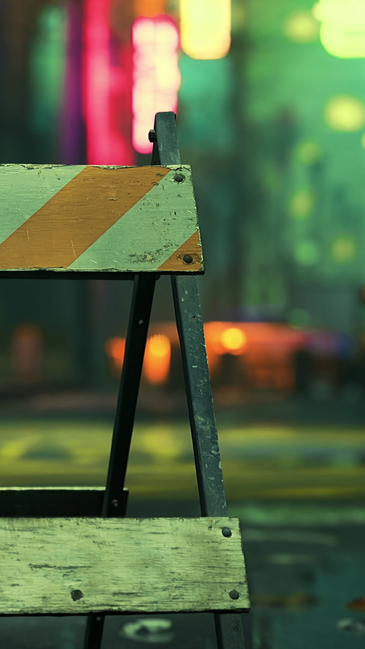 Construction barrier stands on a city street at night with lights in background