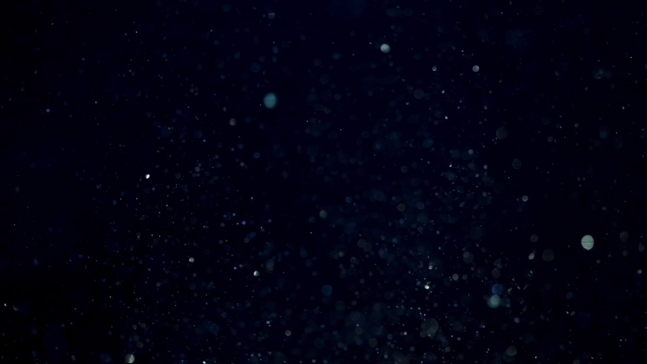 Partículas orgânicas flutuantes à deriva em líquido azul profundo em um cenário macro abstrato, em câmera lenta.