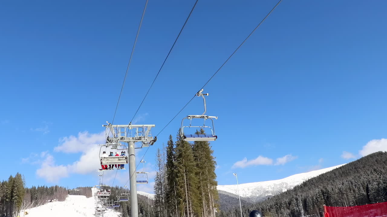 Bukovel, Ukraine - January 20, 2020: People on a moving ski lift at a resort on a sunny day