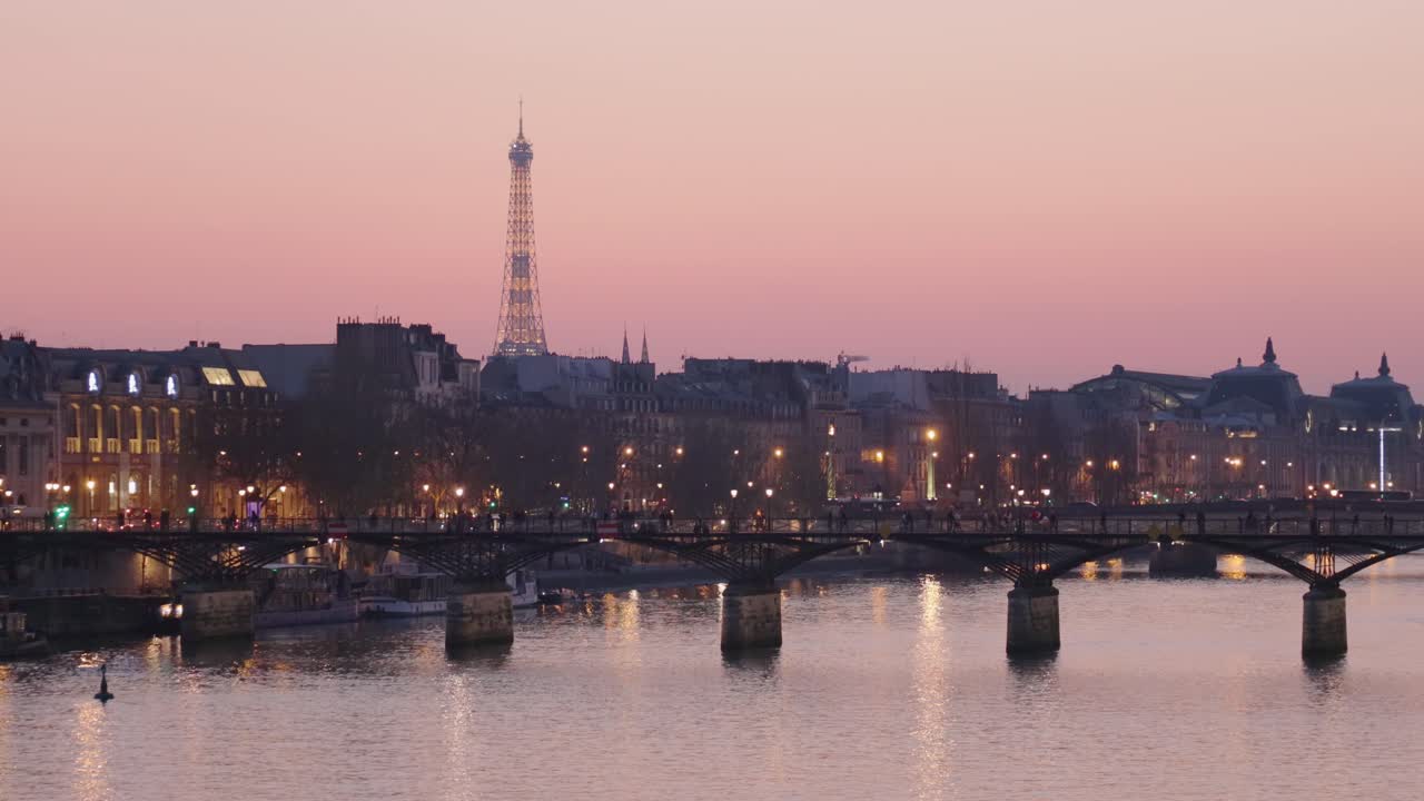 Paris Pont des Arts bridge and Eiffel tower in the distance during evening sunset