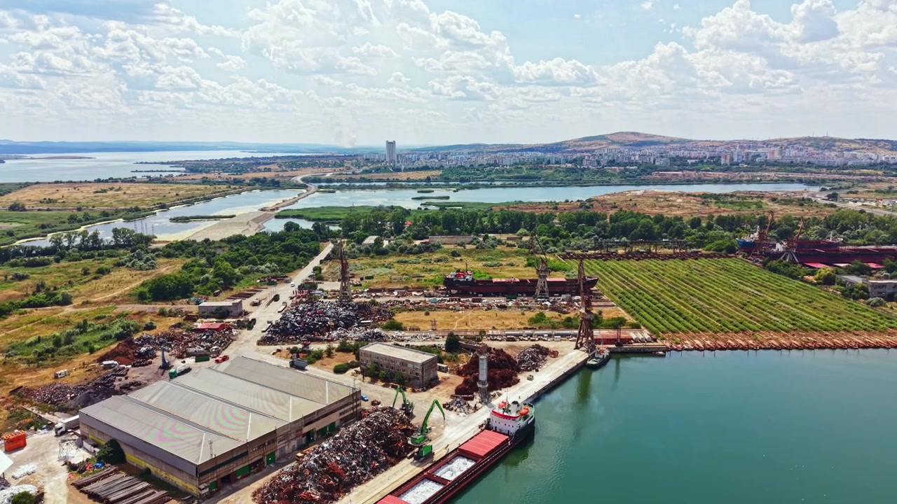 Cantiere navale con gru e acqua vicino alla città, di giorno, in un paesaggio aperto