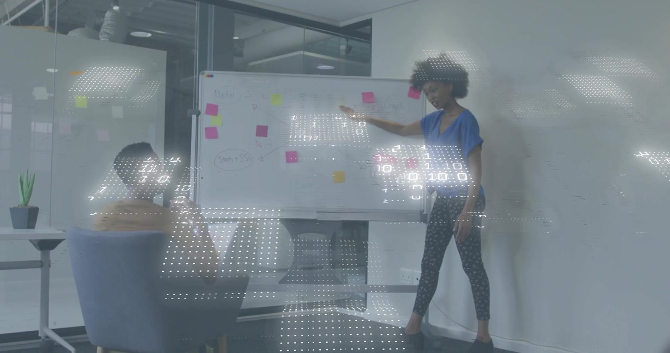 Un relatore indica dei post-it avviando una sovrapposizione binaria mentre un collega risponde in una riunione d'ufficio.