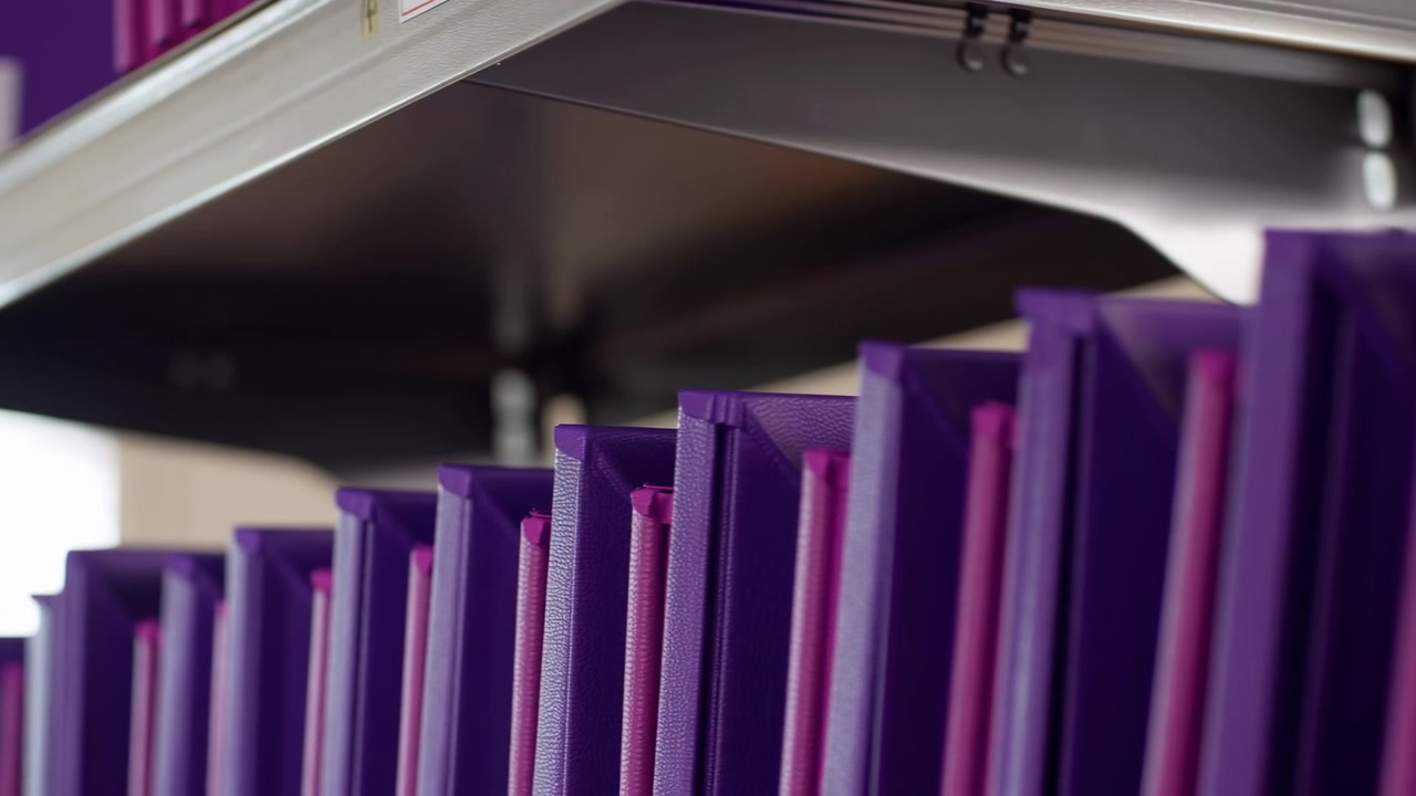 Oggetti cilindrici viola e rosa impilati, nessuna azione o trasformazione visibile, in un ambiente interno con struttura del soffitto, con cilindri viola e rosa, con texture di plastica o cartone.
