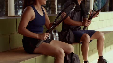 tennis players resting and preparing by the court