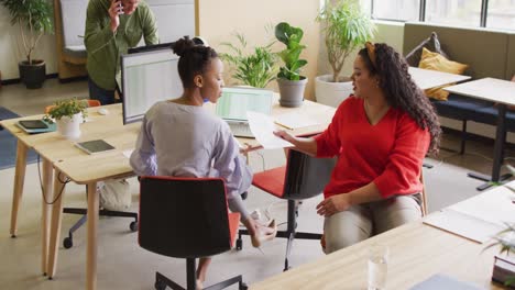 Happy-diverse-business-people-discussing-work-and-holding-documents-at-office