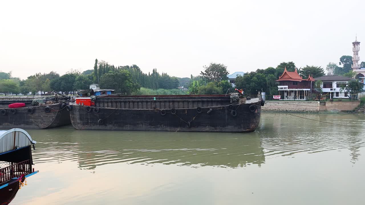 un gran barco de carga se mueve a lo largo del río ayutthaya.
