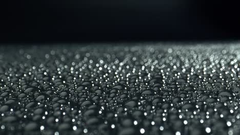 black surface in drops of water. light reflection in the drops.