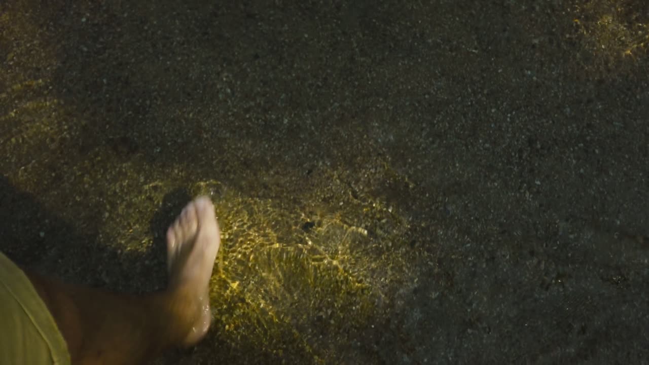 Close up of bare feet stepping in shallow clear clear with sunlight reflections in Yelapa, Jalisco, Mexico