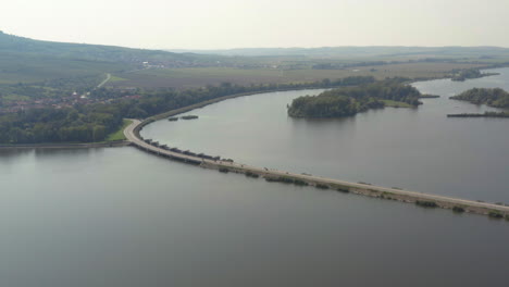 Motos-Conduciendo-Rápido-En-La-Calzada-Del-Embalse-De-Věstonice,-Disparo-De-Drones