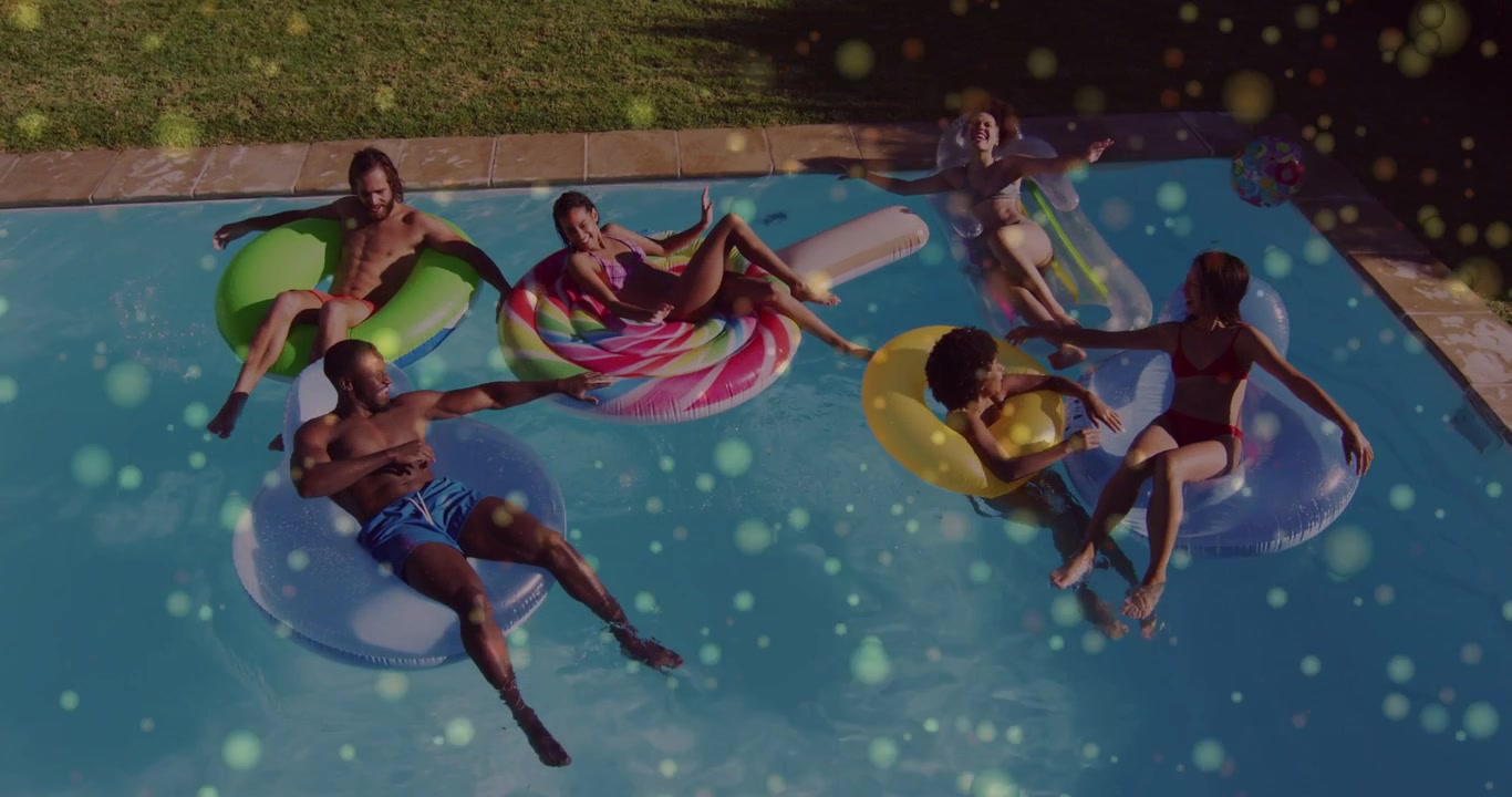 Floating group in swimwear reaching, splashing in yard pool, sunlight glinting on water and floats