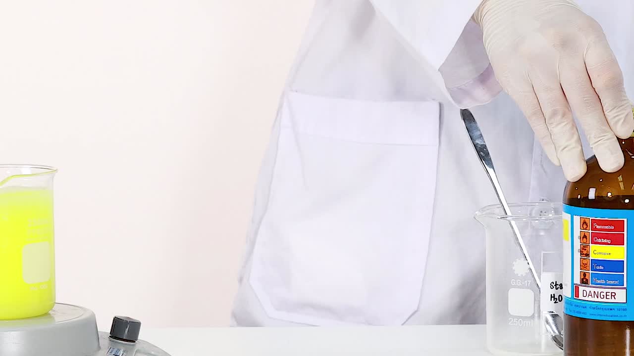 A scientist in a lab coat handles chemical solutions with precision using glassware and a magnetic stirrer.