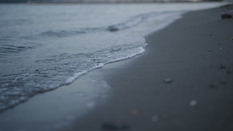 Sanfte-Wellen-Im-Niedrigen-Winkel,-Die-In-Der-Abenddämmerung-Am-Sandstrand-Schwappen,-Naturhintergrund