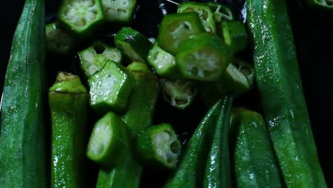 Close-Up-Slow-Motion-Shot-of-Chopped-Green-Chili-Pieces-Falling-Among-other-Chili-Peppers-in-a-Puddle-of-Water