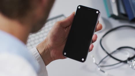médico caucásico que tiene una consulta de videollamada usando un teléfono inteligente