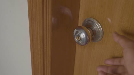 hand opening a wooden door with a metal door handle