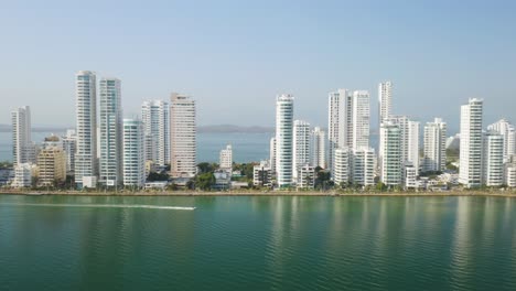 Aerial-Sliding-Shot-Along-Cartagena-Caribbean-Coast-with-Boat-in-Foreground