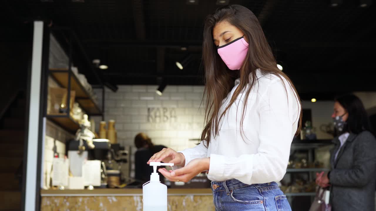 전염병 기간 동안 카페에서 손을 소독하는 여성