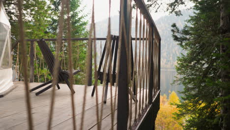 terrace with wooden chairs facing fall nature. place with view of river and mountains directly from balcony of cottage. perfect place for family vacation in countryside