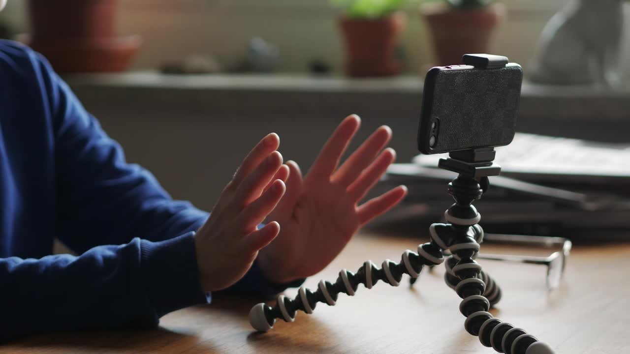 mujer sentada frente al teléfono inteligente en un trípode grabando video