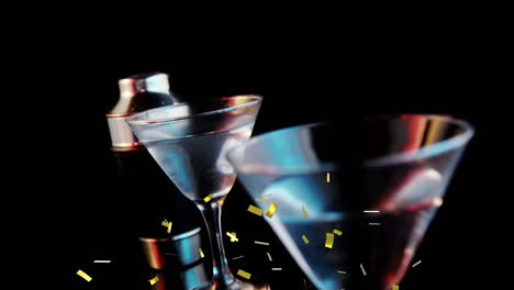 golden confetti falling over olives falling into cocktail glasses against grey background