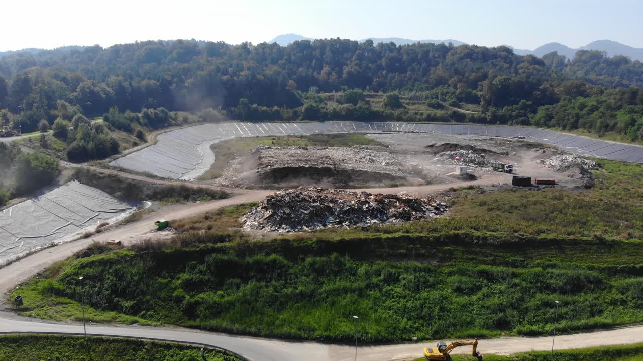 Waste landfill operation full of rubber tires and other trash with machines compacting, Aerial pan right shot