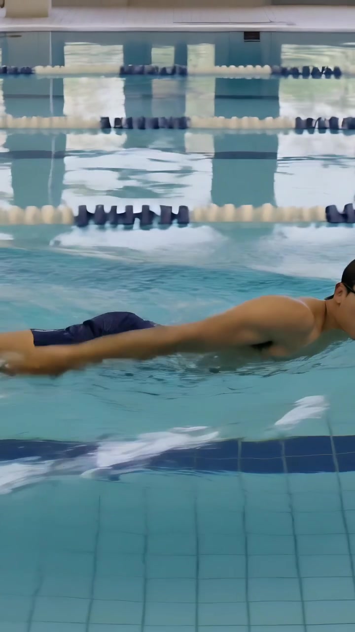 Vertical video: Gliding swimmer powering along lane ropes for laps, goggles and trunks, copy space