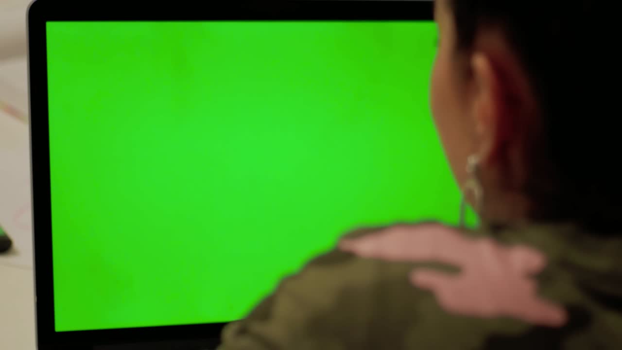 Girl in camouflage clothes makes video call on laptop with green screen