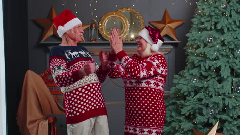 una alegre pareja de ancianos casados, abuelos celebrando el éxito, ganando, gritando, regocijándose en navidad.