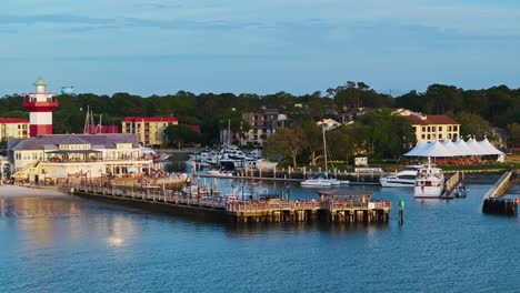 drone pullback over boats near boardwalk and beachside buildings at harbor pier, harbour town pier south carolina usa