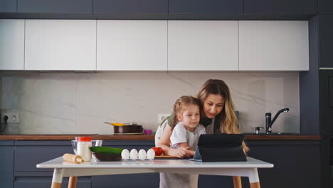 mother and little daughter stand in kitchen