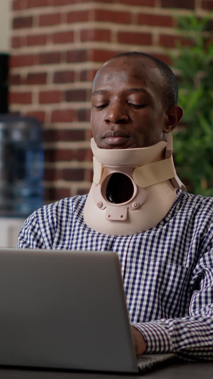Man wearing neck brace using laptop