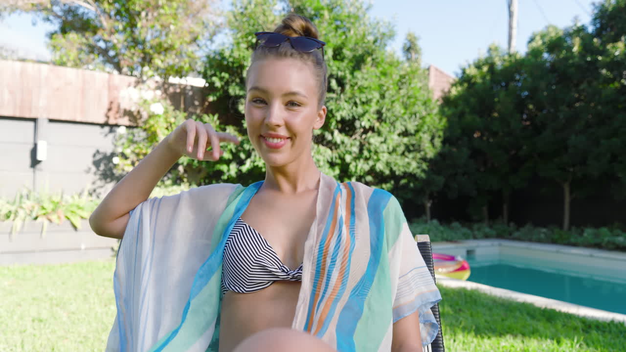 Smiling woman in swimsuit relaxing by pool on sunny day, enjoying leisure time, copy space