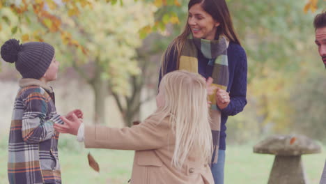 familia con perro mascota jugando y divirtiéndose con los padres arrojando hojas de otoño en el jardín