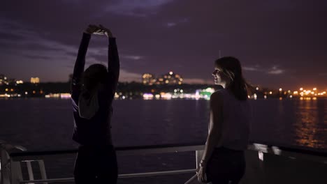 silueta de dos atractivas mujeres jóvenes que viajan en un barco por la noche. amigas en el barco