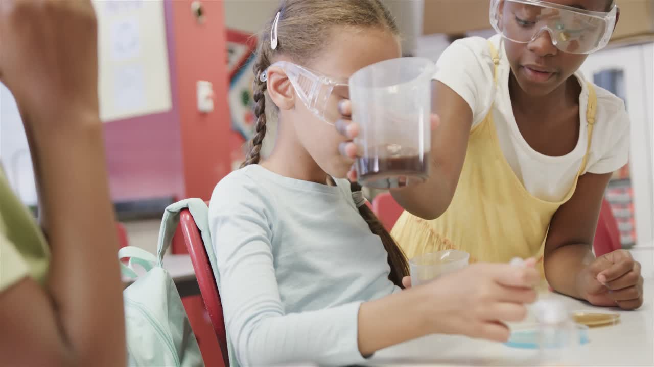 niñas felices y diversas haciendo experimentos en el laboratorio en cámara lenta en la escuela primaria