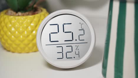 digital thermometer and hygrometer displaying temperature and humidity with plant decor