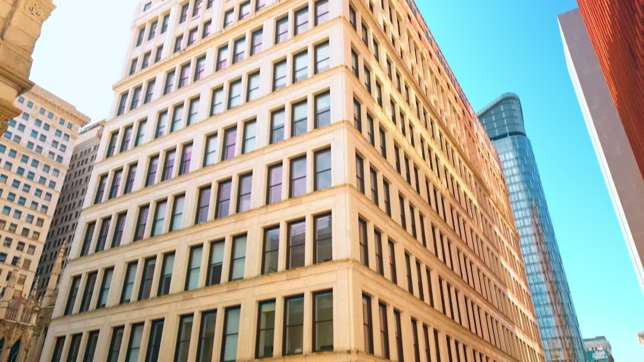 View on the crossroad paved by the red bricks in the street of a modern city. Looking up at the high-rise building on the corner of the street. Pittsburg, Pennsylvania, USA