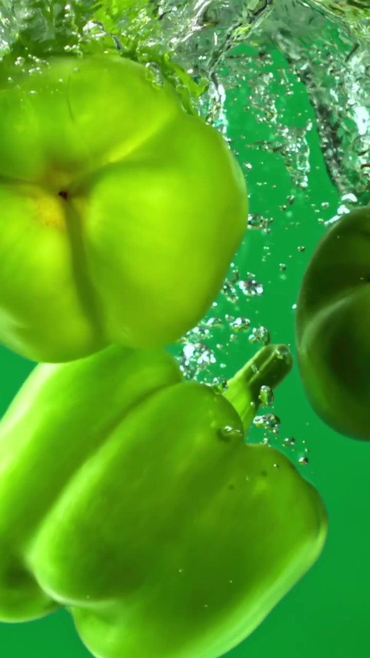 Peperoni verdi freschi che schizzano nell'acqua