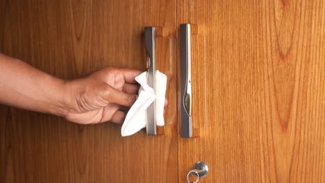 a person cleaning a door handle with a wipe