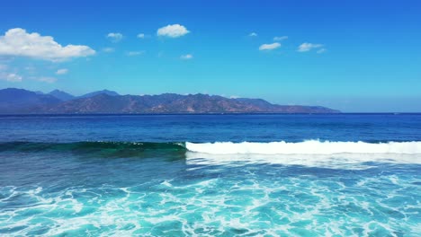 hermosas olas blancas salpicando en la costa de islas tropicales rodeadas de mar azul en un cielo brillante con fondo de nubes, indonesia