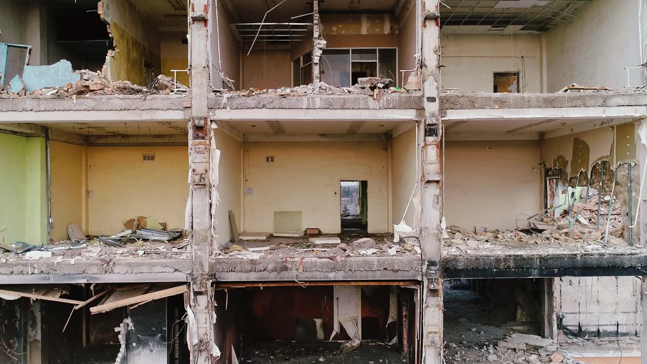 Ripresa aerea verticale ascendente sopra un edificio urbano distrutto, simbolo di perdita post-bellica